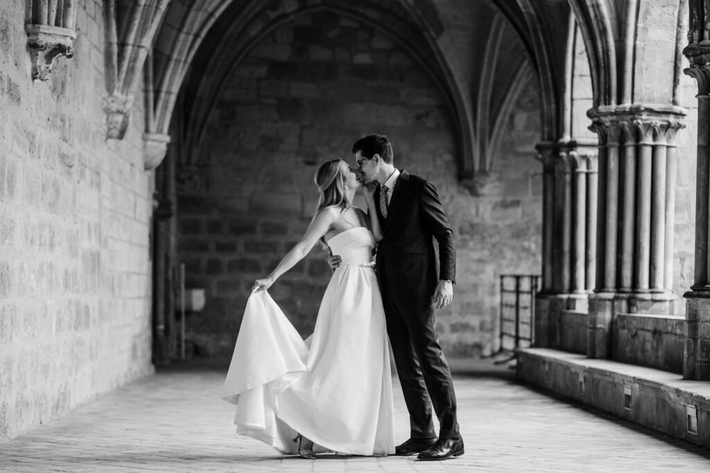 couple de mariés photographié discrètement sous une arche en pierre